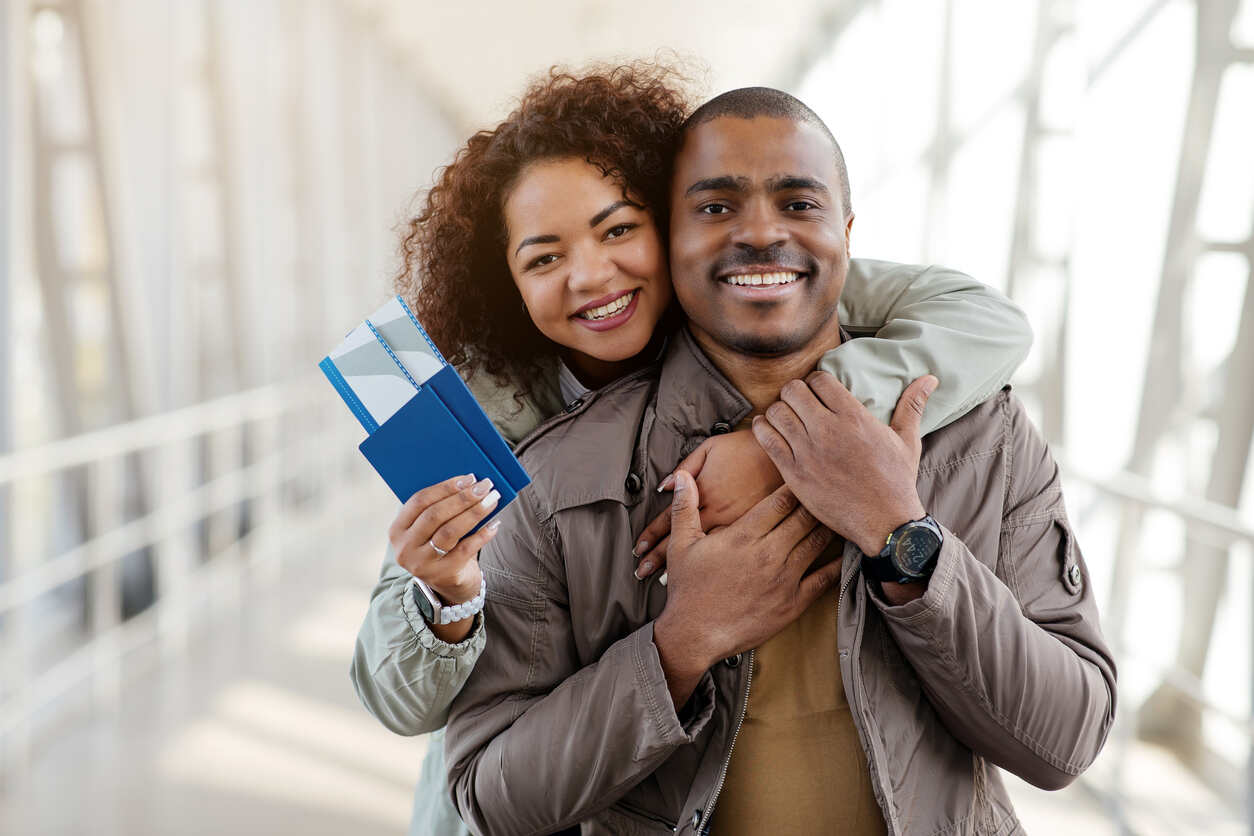 Happy couple holding passports and tickets, illustrating the K-1 visa approval journey and next steps for fiancés adjusting to life in the U.S.