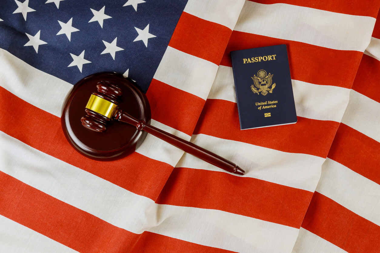 US Passports with wooden judge gavel on American flag representing u visa and non immigrant visa lawyer.