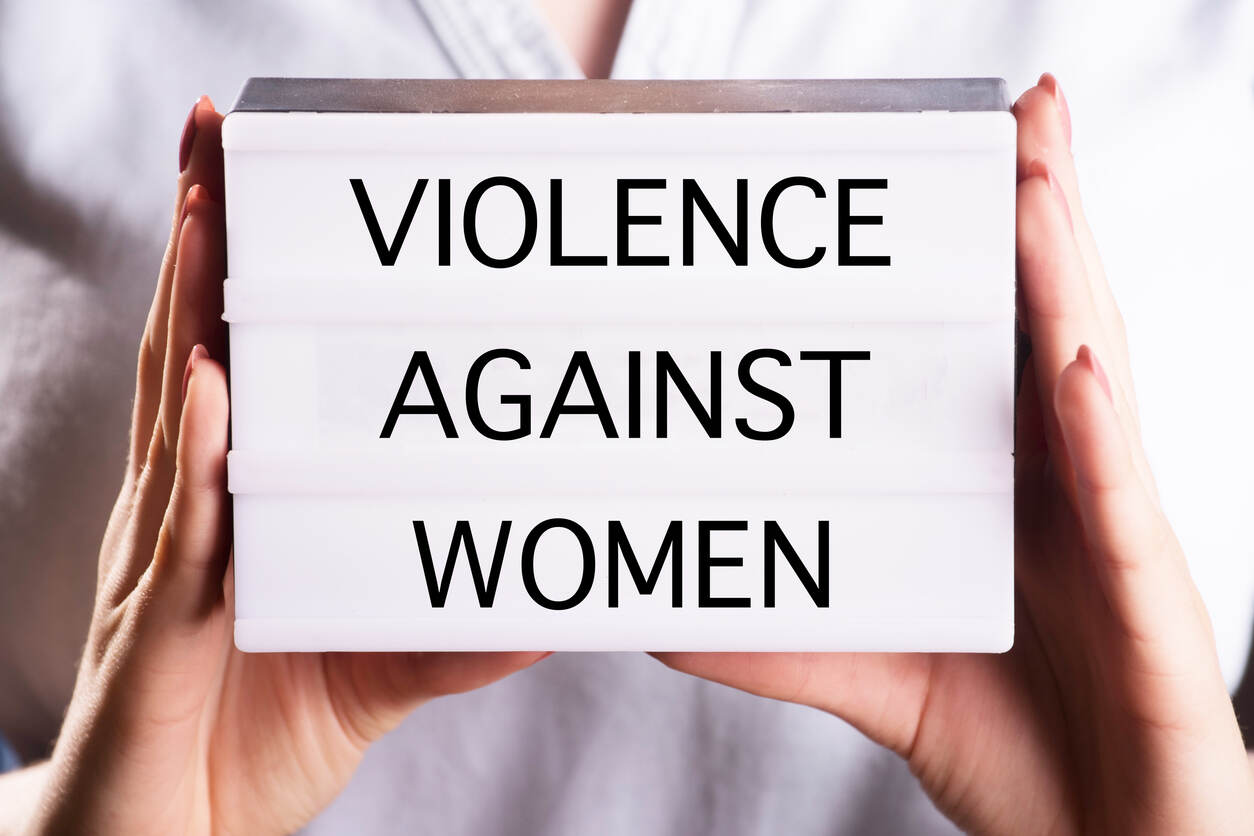 Hands holding a lightbox sign saying 'VIOLENCE AGAINST WOMEN', symbolizing legal support.