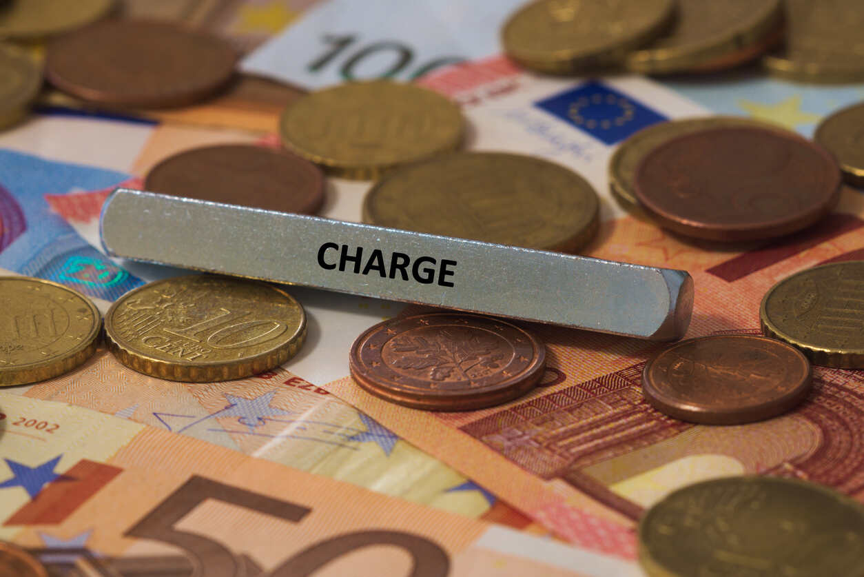 A metallic bar with the word "CHARGE" engraved on it, lying on a bed of Euro banknotes and coins.