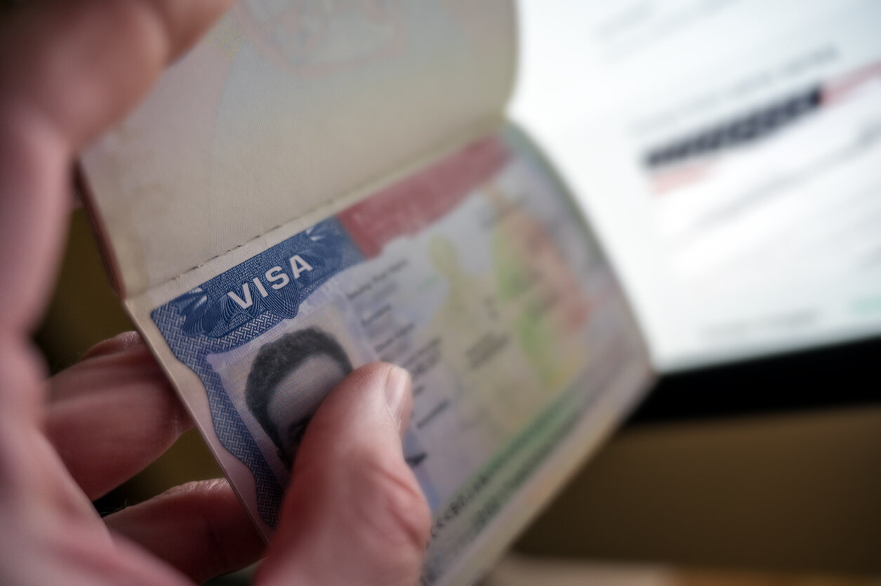 A blurry U.S. visa in a passport held in a hand, illustrating the concept of permanent residency before naturalization.